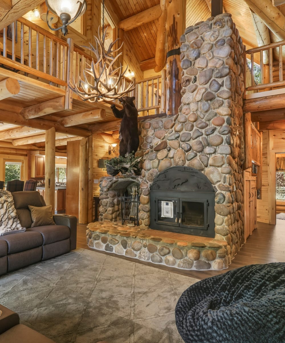 Grand log-cabin great room with a towering river-rock fireplace and antler chandelier, Pagosa Springs